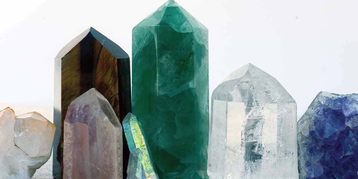 Collection of natural gemstone crystals including emerald, amethyst, clear quartz, and tiger's eye points